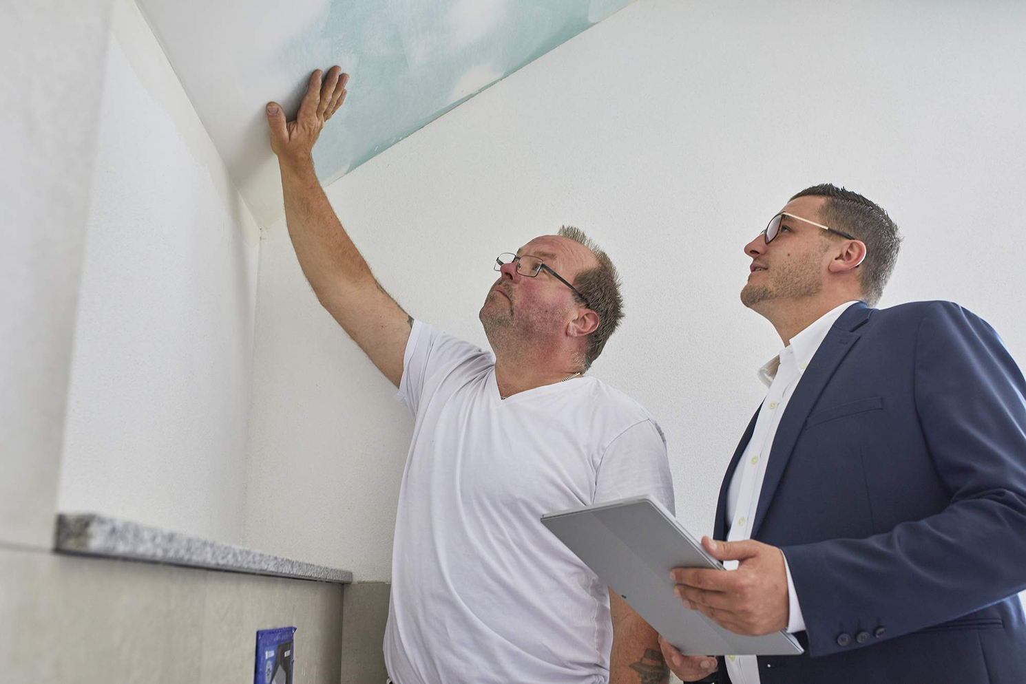 Baubesichtigung mit Frank Schindler und Handwerker – Becker Immobilien Brilon Frank Schindler und ein Handwerker prüfen gemeinsam die Bauarbeiten an einer Zimmerdecke.