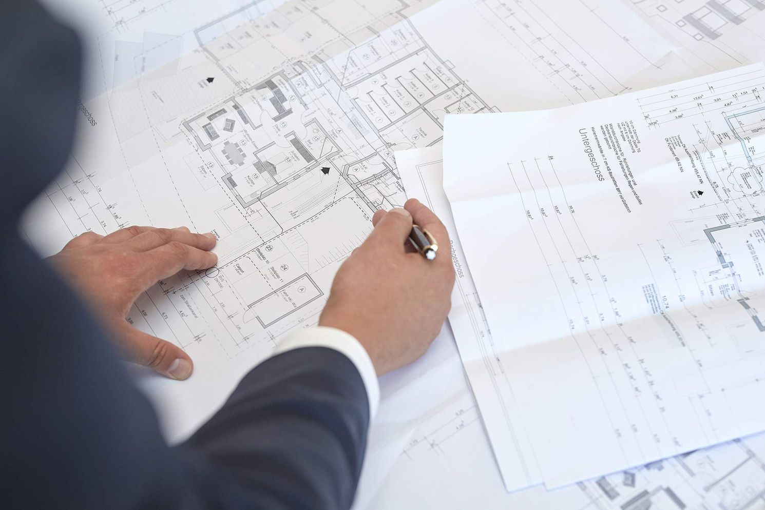 Detailansicht Baupläne – Becker Immobilien Brilon Hand zeigt mit Kugelschreiber auf Baupläne eines Wohnprojekts von Becker Immobilien in Brilon.